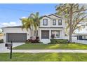 Charming two-story home featuring lush landscaping, front porch, gray double-door entry, and a side-entry garage at 2904 W Averill Ave, Tampa, FL 33611