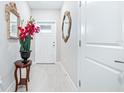 Bright entryway with tiled floor, adorned with decorative mirrors, a decorative flower arrangement, and a white front door at 31408 Cabana Rye Ave, San Antonio, FL 33576
