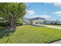 Well-manicured lawn surrounds this home's exterior with a covered carport and mature tree at 3252 Scorecard Dr, New Port Richey, FL 34655