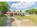 Charming single-story home featuring a bright red door, carport, and a spacious front yard with mature trees at 3502 Bloomingdale Ave, Valrico, FL 33596