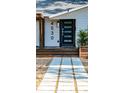 Close-up of a home's modern black front door and inviting wooden porch with planters at 4530 5Th S Ave, St Petersburg, FL 33711