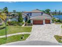 Beautiful home with a three-car garage, lush landscaping, and a brick paver driveway at 4803 Longwater Way, Tampa, FL 33615