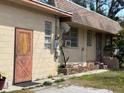 Side view of a single-story home with tan siding, a red door, and an outdoor utility access at 5217 18Th S Ave, Gulfport, FL 33707