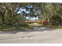 A home with a classic ranch style, set back with a long driveway, fence and vibrant bushes at 9825 Casey Dr, New Port Richey, FL 34654