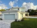 Charming two-story home showcasing a well-manicured lawn and a light blue garage door, with a delightful sky backdrop at 11598 Oak Ln, Largo, FL 33778