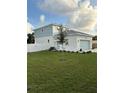 This exterior features white and light blue siding, a well-maintained lawn, and a white fence for added privacy at 11598 Oak Ln, Largo, FL 33778