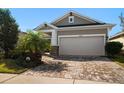 Single-story home features a two-car garage and brick-paved driveway complemented by manicured landscaping at 13917 Kingfisher Glen Dr, Lithia, FL 33547