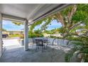 Covered outdoor patio space with a table and chairs, surrounded by lush landscaping at 1496 Queen Anne Dr, Palm Harbor, FL 34684
