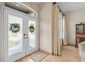 Bright foyer featuring double glass doors, neutral tile flooring, and elegant window at 2050 N Pointe Alexis Dr, Tarpon Springs, FL 34689