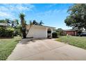 Home with white exterior paint and a concrete driveway surrounded by some well manicured landscaping at 2127 Scotland Dr, Clearwater, FL 33763