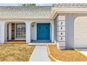 Inviting home entrance featuring a bright blue door and lovely landscape detail at 3543 Rockaway Dr, Holiday, FL 34691