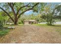 Wide exterior view showcasing home's architecture and spacious, treed front yard at 6231 Massey Rd, Zephyrhills, FL 33542