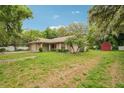 Property with well-manicured lawn, mature trees, attached garage, and red storage shed at 6231 Massey Rd, Zephyrhills, FL 33542