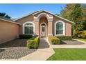 Inviting home entrance with arched doorway, manicured hedges, and lovely landscaping at 775 Brittany Park Blvd, Tarpon Springs, FL 34689