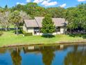 Back view of a serene home overlooking a tranquil lake surrounded by lush greenery and mature trees at 10 James Ct, Oldsmar, FL 34677