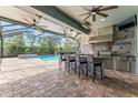 Amazing outdoor kitchen by the pool, featuring stainless steel appliances, bar seating, and stylish decor at 10007 Hazelnut Ct, Tampa, FL 33647