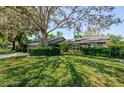 Brick home featuring lush green lawn and mature trees providing shade and curb appeal at 11510 Moffat Pl, Temple Terrace, FL 33617