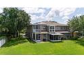Spacious backyard featuring a screened porch, green lawn, and the back view of the house at 12170 Lake Allen Dr, Largo, FL 33773