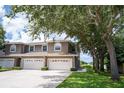 Townhouse exterior featuring a two-car garage, well-maintained lawn, and mature trees providing shade at 12170 Lake Allen Dr, Largo, FL 33773