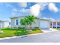 Charming home featuring a well-manicured lawn, lush palms, and an attached garage at 12501 Ulmerton Rd # 14, Largo, FL 33774