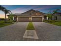 Beautiful home exterior with manicured lawn, a stone facade, and a double driveway leading to attached garages at 19370 Hawk Valley Dr, Tampa, FL 33647