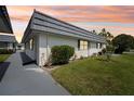 Attractive white single-story home featuring a well-manicured lawn and mature landscaping during sunset at 205 Andover N Pl # 110, Sun City Center, FL 33573