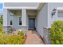 Inviting entryway with a blue front door, stone accents, brick path, and lush landscaping at 2121 Secret Cv, Odessa, FL 33556
