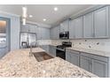 Modern kitchen boasts stainless steel appliances, gray cabinets, granite counters and a large island with sink at 2121 Secret Cv, Odessa, FL 33556