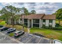 Aerial view showcases the condo's facade, parking and mature trees at 2699 Pine Ridge E Way # H1, Palm Harbor, FL 34684