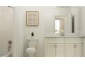 Bright bathroom with white subway tile, a white vanity with marble countertop, and a framed art piece above toilet at 31719 Griffin Sands Ln, San Antonio, FL 33576