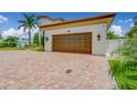 Attached two-car garage featuring paneled doors and exterior sconces, complemented by a brick-paved driveway at 362 41St Ave, St Pete Beach, FL 33706