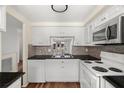 Clean kitchen with white cabinets, white appliances and dark countertops, plus view to outdoor living area at 4227 Glissade Dr, New Port Richey, FL 34652