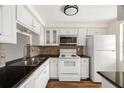 Functional kitchen features white appliances, cabinets, and a stylish backsplash, complemented by dark countertops at 4227 Glissade Dr, New Port Richey, FL 34652