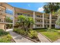 A view of the condo's exterior, showing multiple levels, black metal balconies, and lush, tropical landscaping at 870 Virginia St # 109, Dunedin, FL 34698