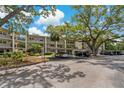 Exterior view showing parking with covered spaces, landscaping, and multiple condo units in the background at 870 Virginia St # 109, Dunedin, FL 34698