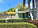 Charming home featuring a vibrant green facade, a cozy porch, and lush landscaping for enhanced curb appeal at 126 Orangewood Dr, Dunedin, FL 34698