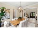 Dining room with a modern chandelier, wood table, and archway leading to the grand foyer with natural light at 16119 Carencia Ln, Odessa, FL 33556