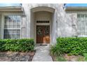 Inviting entryway featuring double doors, sidelights, decorative wreaths, and lush green landscaping at 19106 Abercorn Pl, Lutz, FL 33558