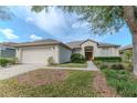 Attractive home showcasing a two-car garage, well-maintained lawn, and charming entryway with sidelights at 19106 Abercorn Pl, Lutz, FL 33558