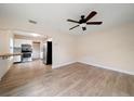 Open-concept living room with a ceiling fan, wood floors, and a view into the adjacent kitchen at 2585 9Th N Ave, St Petersburg, FL 33713