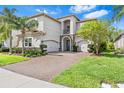 Beautiful home showcasing a brick paver driveway, a manicured lawn, and a covered entryway at 30900 Spruceberry Ct, Wesley Chapel, FL 33543