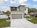 View of a modern house with a two-car garage, stylish exterior, and a manicured lawn at 3108 W Ballast Point Blvd, Tampa, FL 33611