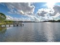 Scenic lake view showcasing calm waters and a wooden dock under a partially cloudy sky at 3207 Lake Padgett Dr, Land O Lakes, FL 34639