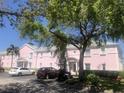 Exterior view of a two-story condo building with white trim, cars in parking lot, and mature trees at 4794 Cobia Se Dr # D, St Petersburg, FL 33705