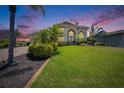 Stately home with lush lawn, mature landscaping, and a grand entrance, bathed in the soft glow of twilight at 706 Bunker View Dr, Apollo Beach, FL 33572