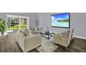 Comfortable living room featuring stylish furniture, wood floors, and a serene coastal view on the television at 11831 Lancashire Dr, Tampa, FL 33626
