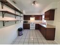 Functional kitchen with wood cabinets, white appliances, and durable tile flooring at 204 Shore W Dr, Oldsmar, FL 34677