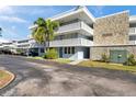 Condo building featuring stone accents, a palm tree, and lattice balconies against a partly cloudy blue sky at 4720 Locust Ne St # 206, St Petersburg, FL 33703