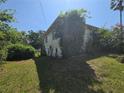 Side view of a house with overgrown landscaping on a sunny day at 613 Chestnut St, Oldsmar, FL 34677
