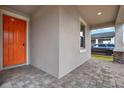 A welcoming covered front porch with brick flooring, gray siding, and a vibrant orange front door at 7336 Bagley Cove Ct, Sun City Center, FL 33573